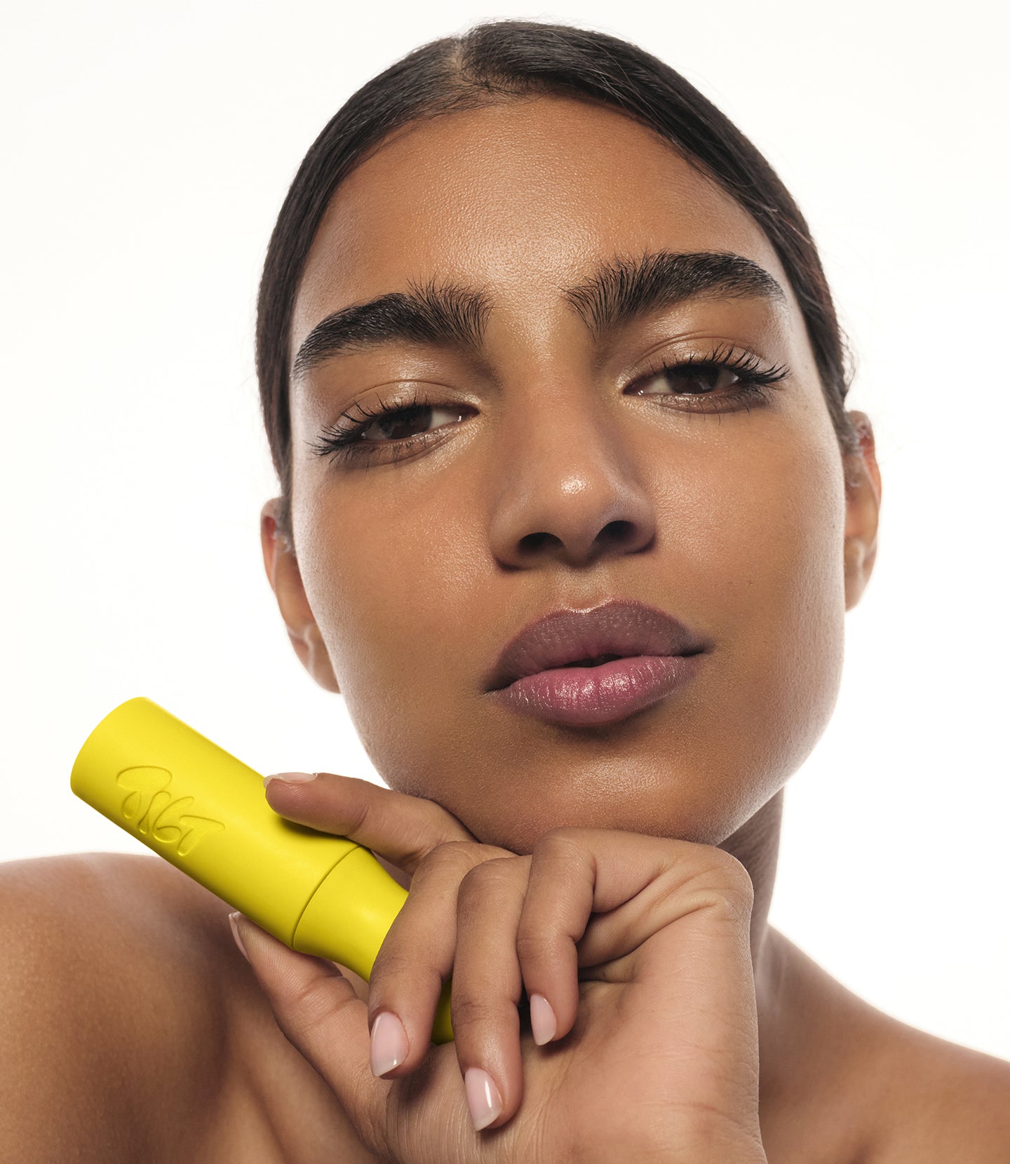 Woman wearing mascara with long eyelashes holding yellow case