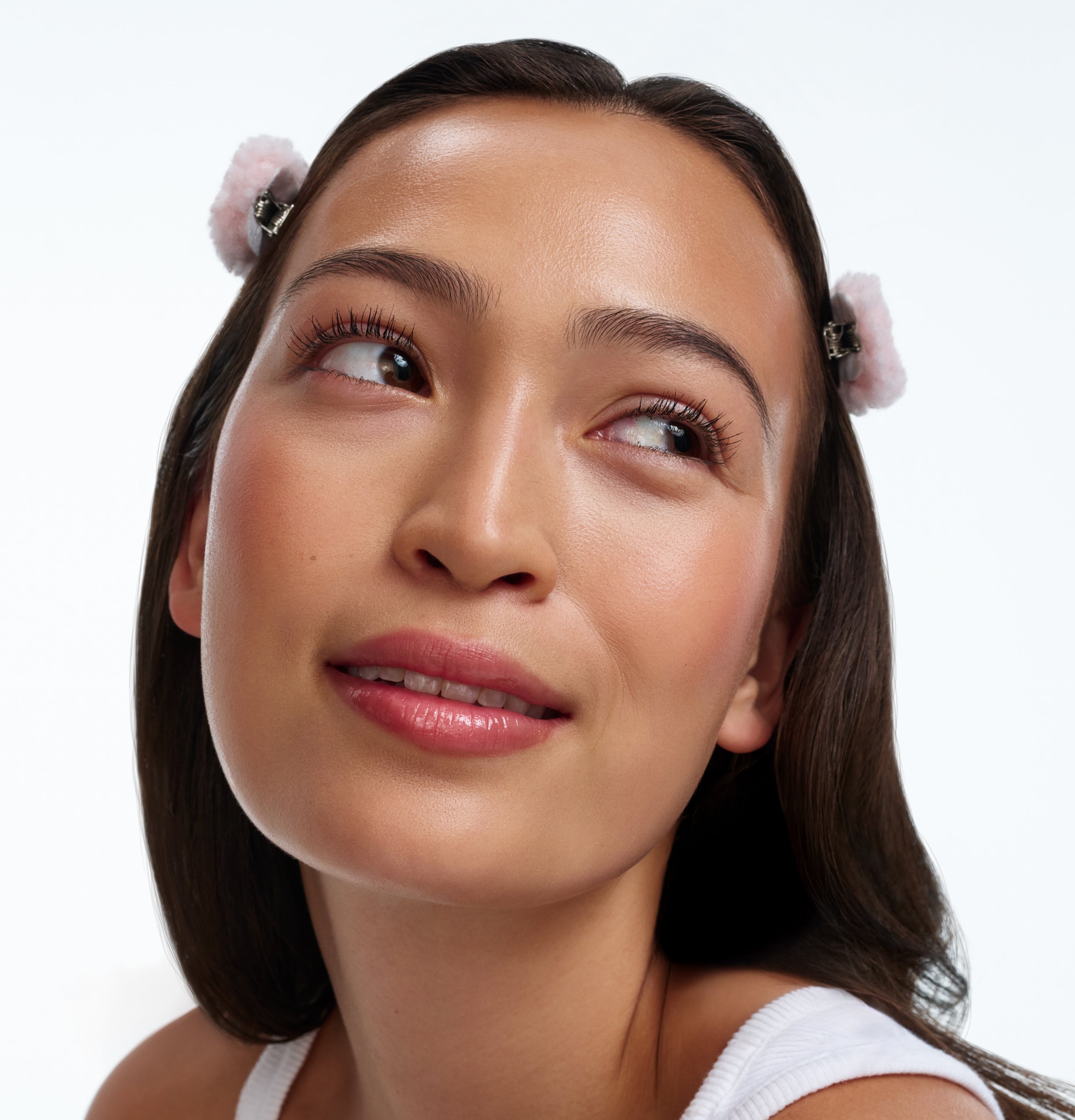 Woman looking off to the right wearing 2 pink fluffy hair clips with 'Tilt' in gold.