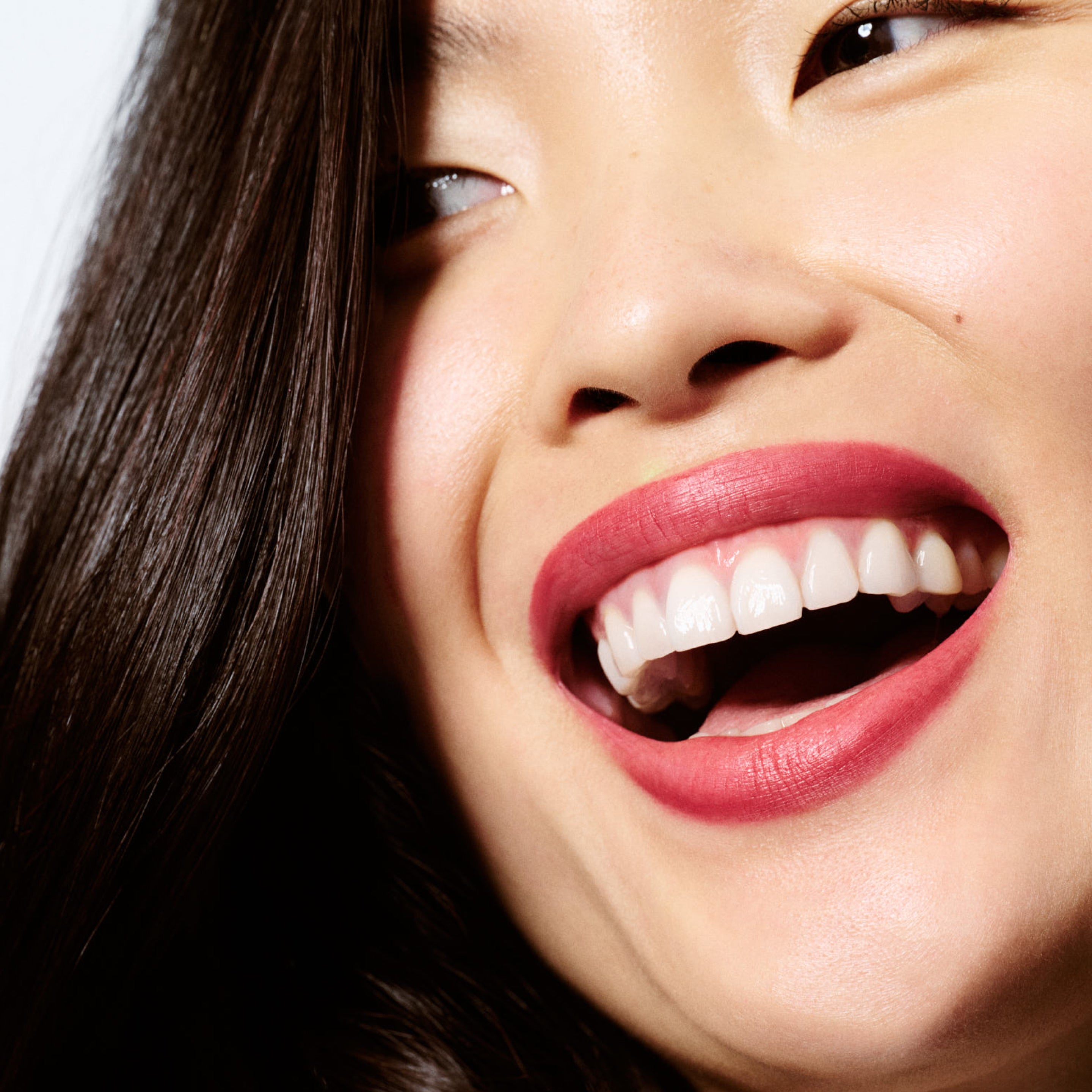 Close-up of a woman's face with a bright smile, wearing a lip liner in a rich berry mauve shade.