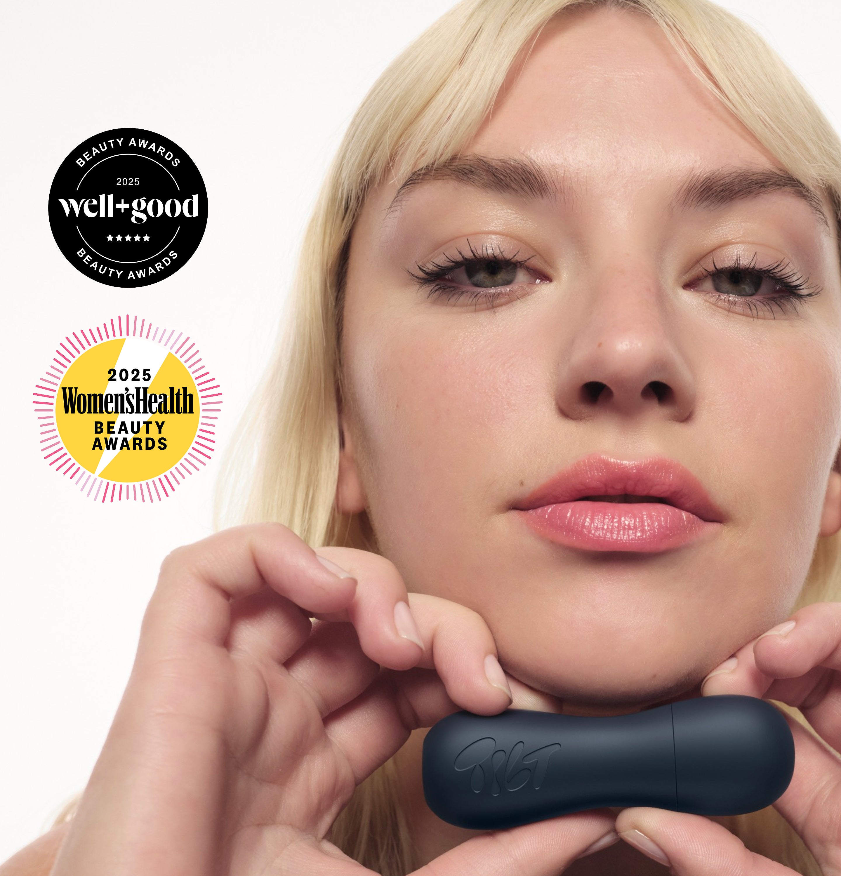 Woman with blonde hair holds a dark navy Grip Stick under her chin. 2025 Well+Good and Women’s Health Beauty Awards badges appear beside her.